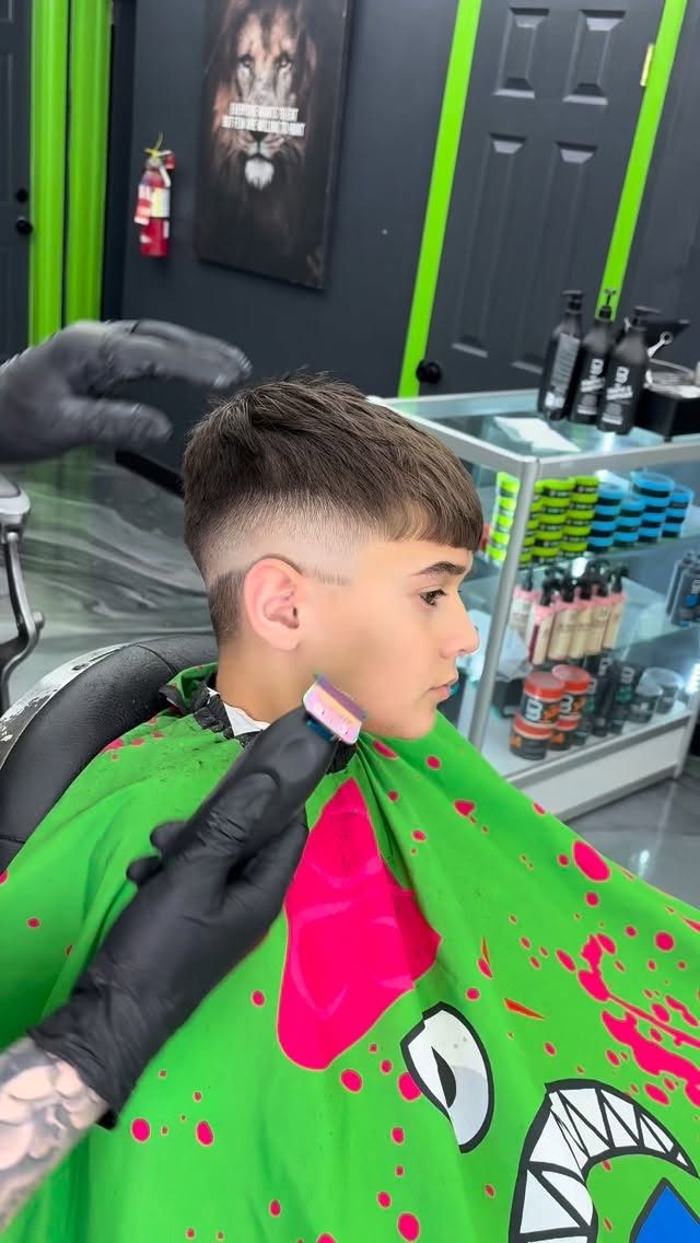 Young client with a high fade and textured top, gloved hand holding a trimmer
